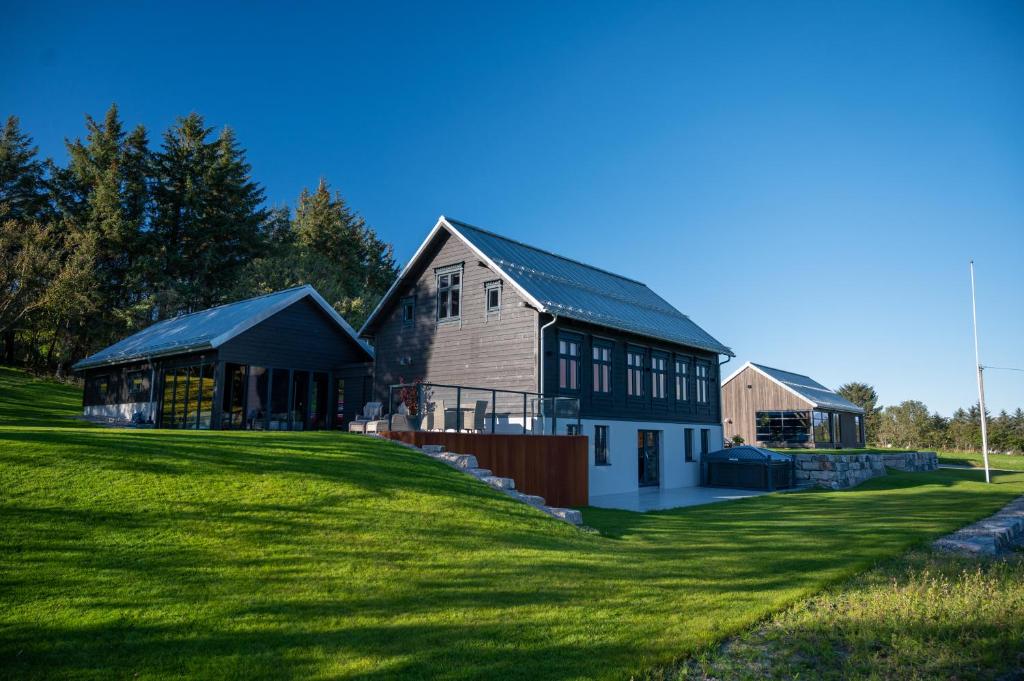 ein großes Haus auf einem Grasfeld neben einem Gebäude in der Unterkunft Godo Lodge in Godøy