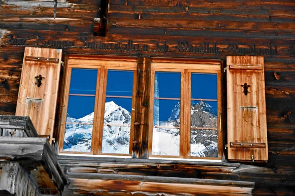 a window of a log cabin with a view of a mountain at Peacefull Mountains View in Kandersteg