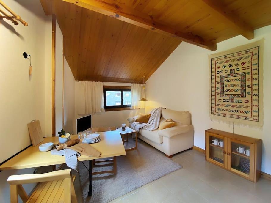 ein Wohnzimmer mit einem Sofa und einem Tisch in der Unterkunft Dúplex abuhardillado con vistas y parking in Vielha e Mijaran