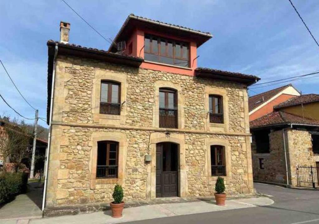 un grande edificio in pietra con tetto rosso di Pantin Corao Casa Rural a Cangas de Onís