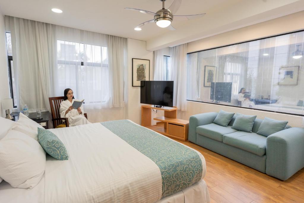 una mujer en una habitación de hotel con una cama y un sofá en Suites Coben Apartamentos Amueblados en Ciudad de México