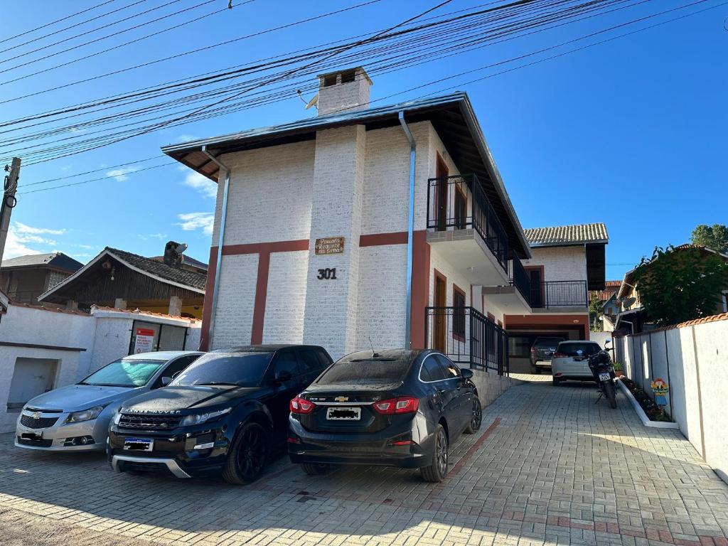 two cars parked in front of a building at Pousada Requinte da Serra in Monte Verde