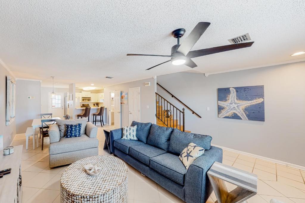 a living room with a blue couch and a ceiling fan at Sweet Spot at Woodland Shores in Destin