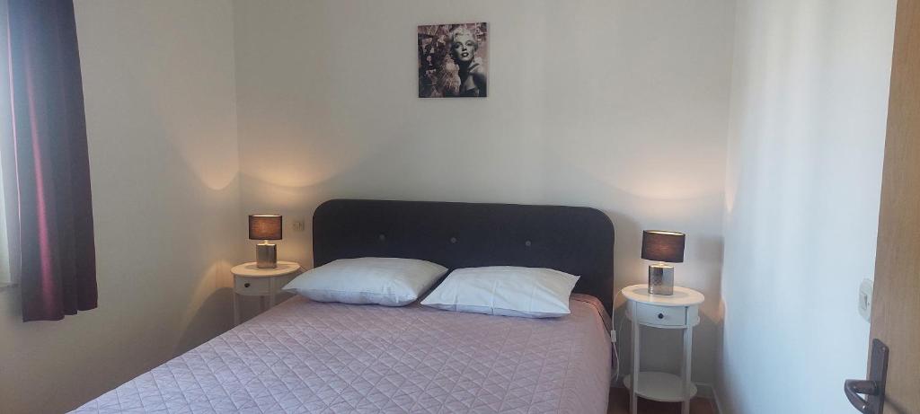 a bedroom with a bed with two pillows and two lamps at Apartments Donadic I, Caska in Novalja