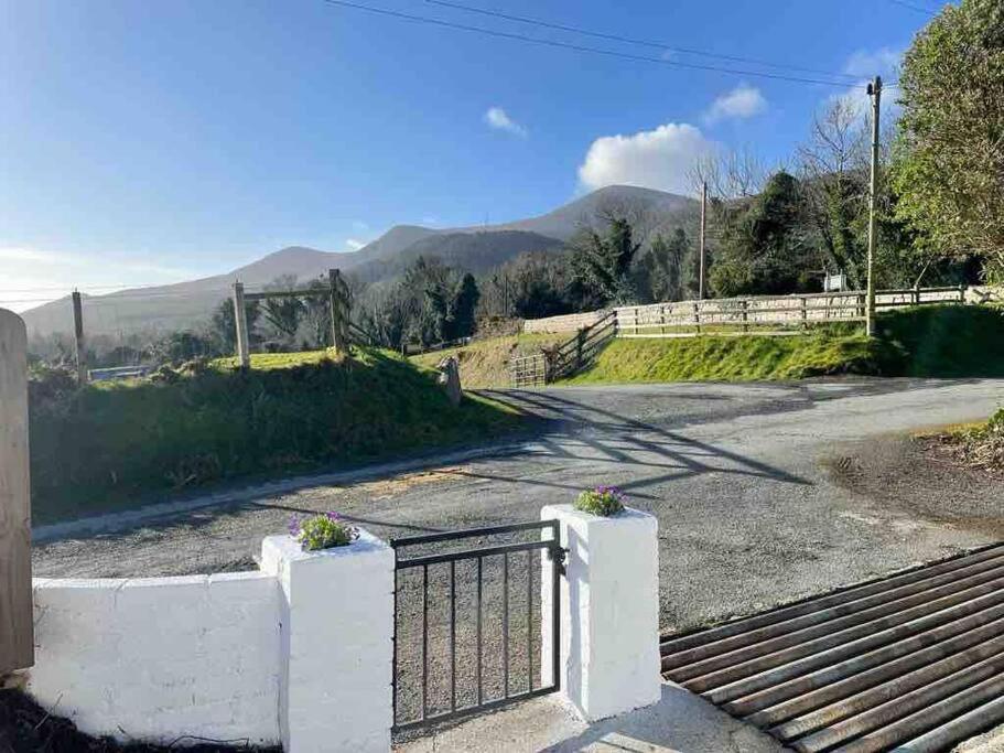 a gate on a road with mountains in the background at Tullybrannigan Cottage Newcastle in Newcastle