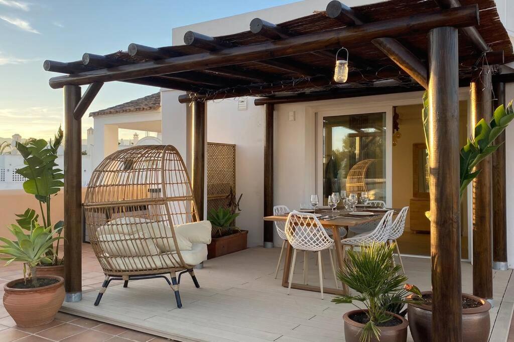 un patio con jaula para aves, mesa y sillas en Luxurious penthouse with 180m2 sunlit terrace, en Estepona