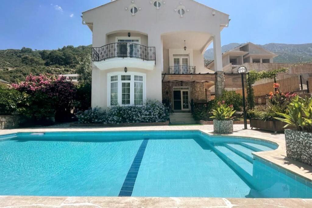 a villa with a swimming pool in front of a house at A quiet, peaceful accommodation in Fethiye