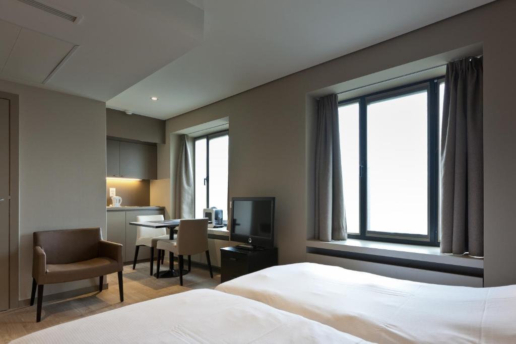 een hotelkamer met een bed, een bureau en een televisie bij Castelnou Aparthotel in Gent