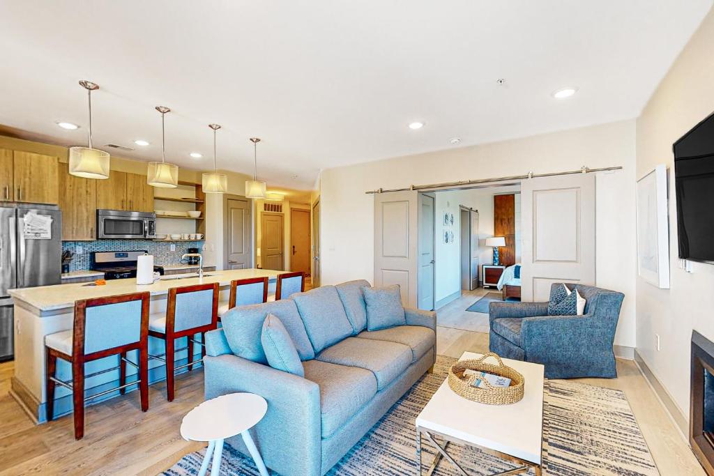 Una sala de estar con un sofá azul y una cocina. en The Pointe 131, en Inlet Beach