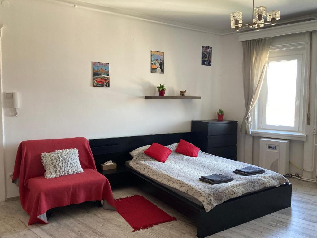 ein Schlafzimmer mit einem Bett und einem roten Stuhl in der Unterkunft Mester24 Apartman in Budapest