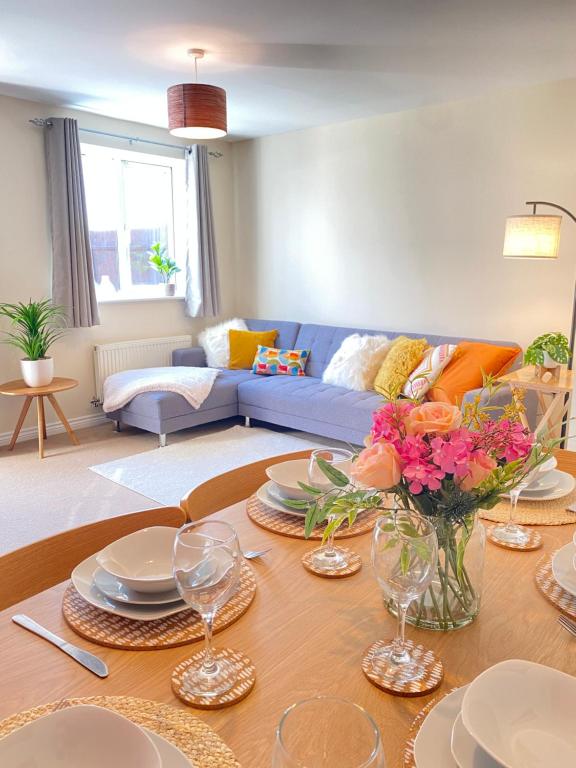ein Wohnzimmer mit einem Tisch und einem blauen Sofa in der Unterkunft Oakley House - Spacious 3 Bedroom, Garden and Parking in Corby