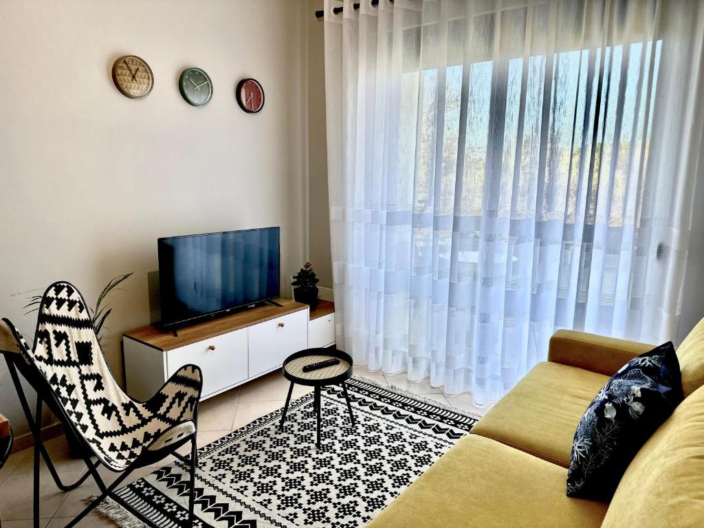 een woonkamer met een bank, een tv en een raam bij Cheerful 2-bedroom apartment in Golem in Golem