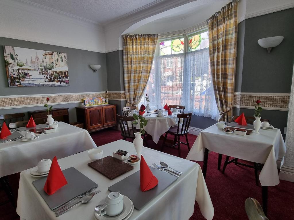 een restaurant met twee tafels met rode servetten erop bij Collingwood Hotel in Blackpool