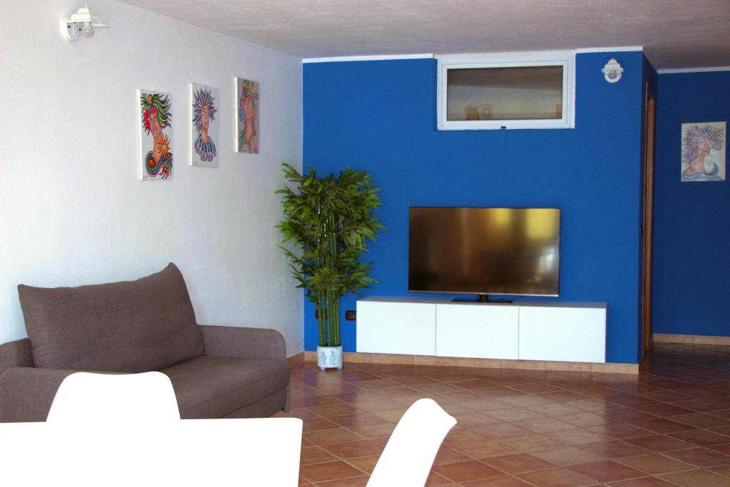 een woonkamer met een tv en een blauwe muur bij Nice and cozy apartment in Àrbatax