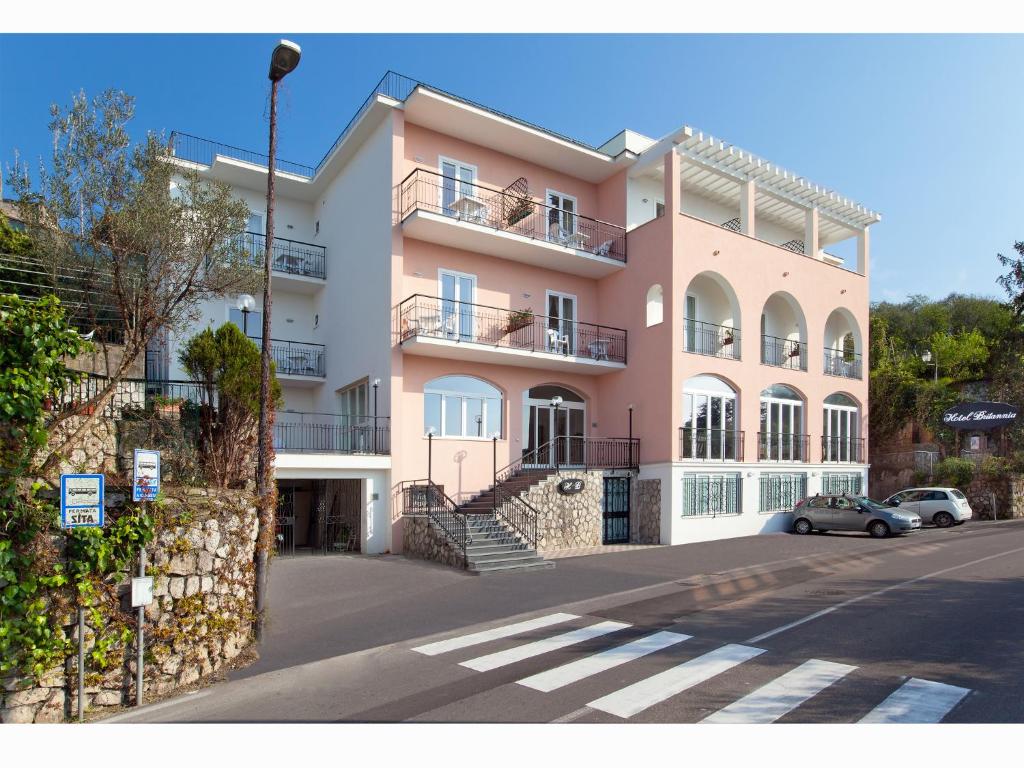 a pink building with cars parked in front of it at Hotel Britannia in Sorrento