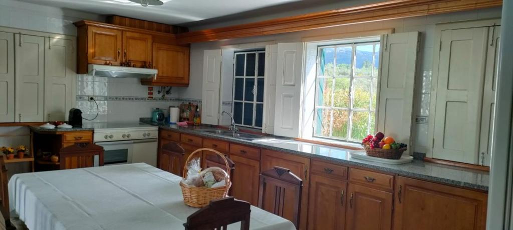 a kitchen with wooden cabinets and a table with a basket of fruit at Quinta da Barbosa in Folgosinho