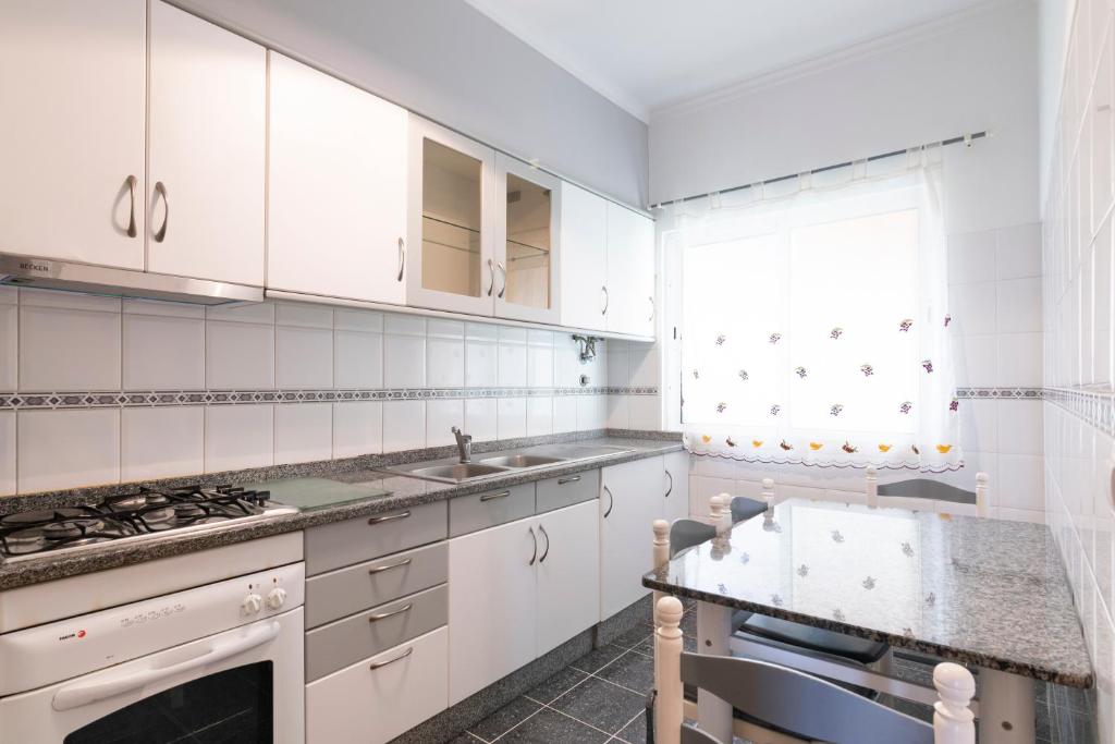 uma cozinha branca com armários brancos e um lavatório em Eddy´s House em Santa Cruz - Madeira