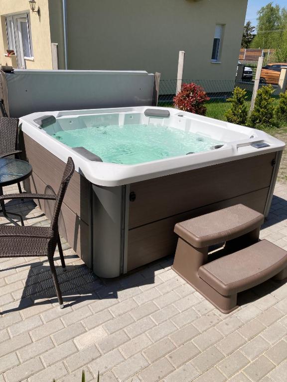 a hot tub sitting on a patio with a chair at Konrad Apartman in Balatonmáriafürdő