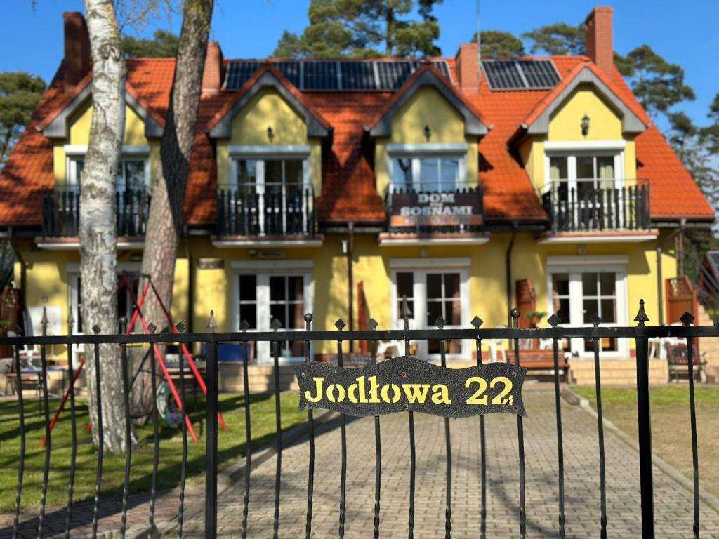 a house with a sign in front of a fence at Dom pod Sosnami in Pobierowo
