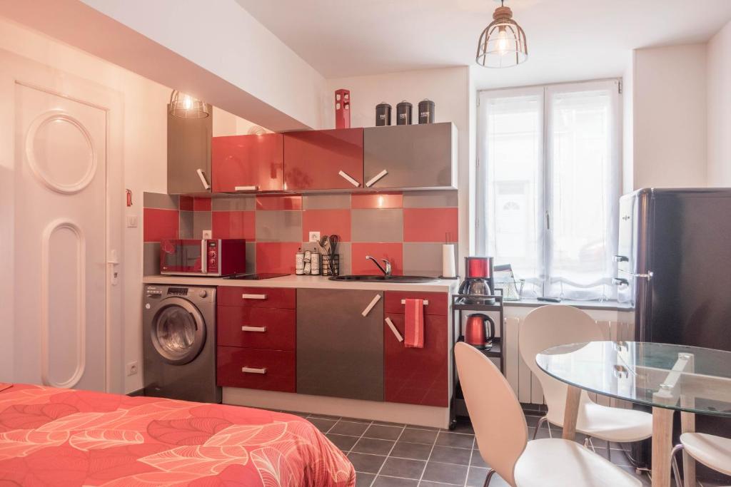 uma cozinha com armários vermelhos e uma mesa num quarto em Studio Le Ligérien em Saint-Denis-de lʼHôtel
