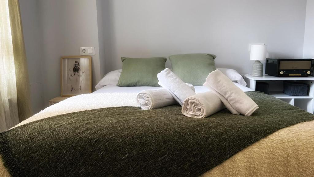 Una cama con dos toallas enrolladas encima. en La casita de Maria, en Getxo