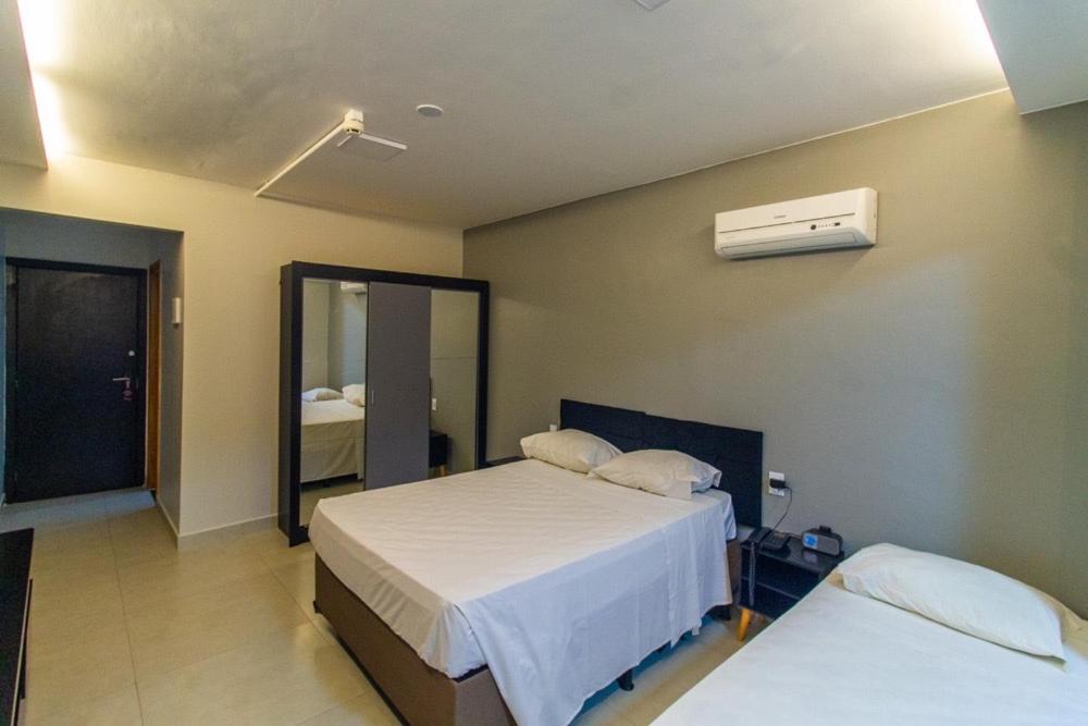 a hotel room with two beds and a mirror at Garvey Park Hotel - apartamento particular 629 in Brasilia