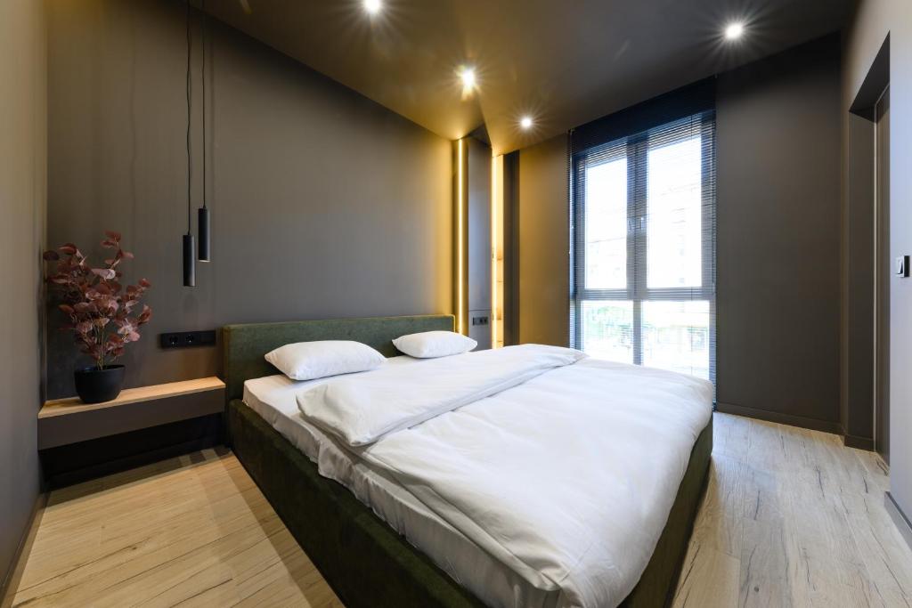 - une chambre dotée d'un grand lit avec des draps blancs et une fenêtre dans l'établissement Luxury Apartments-Belochka, à Oujhorod