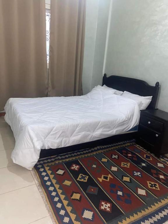 a bedroom with a bed with a rug on the floor at Shams doha in Beni Mellal