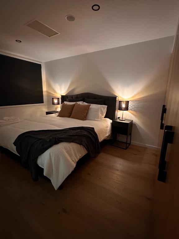 a bedroom with a large white bed with two lamps at Palko - Luxury In the City in Canberra