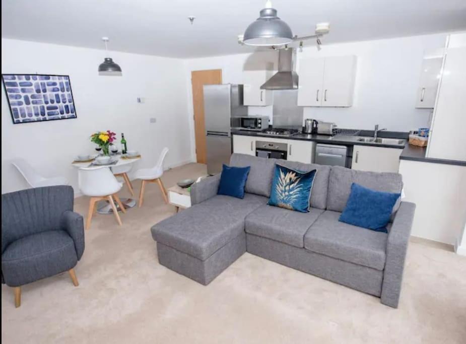 a living room with a gray couch and a kitchen at 1 Bedroom flat in Peterborough City centre in Peterborough