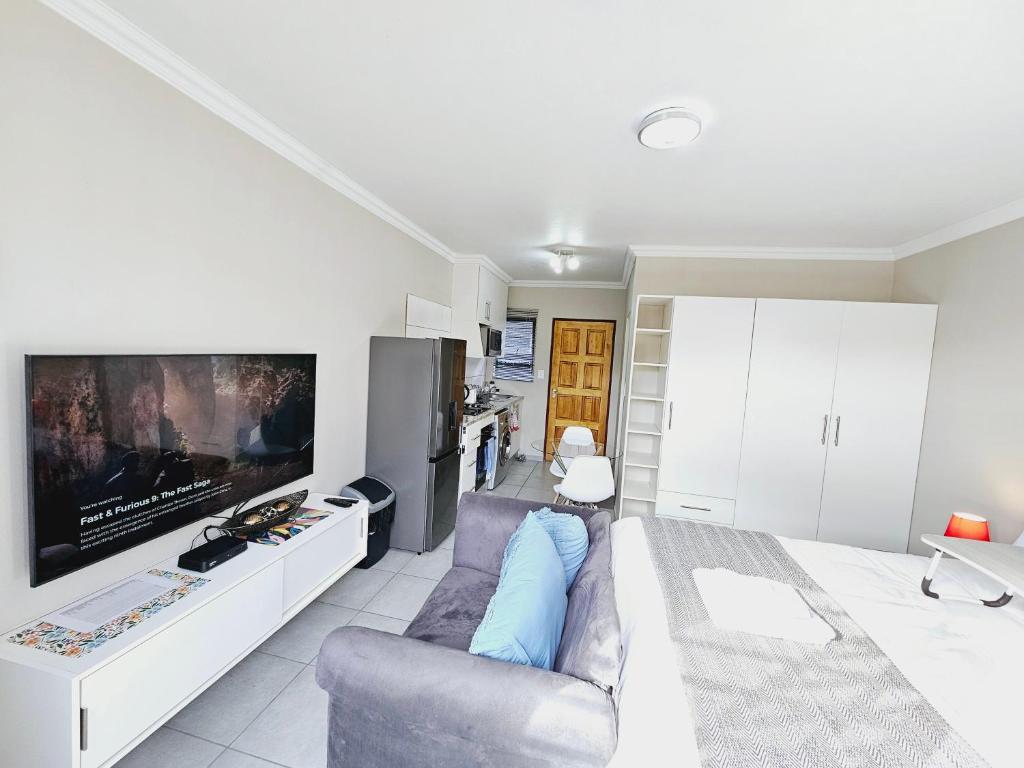 a living room with a couch and a tv at Quantum Heights - Studio Apartment in Fourways