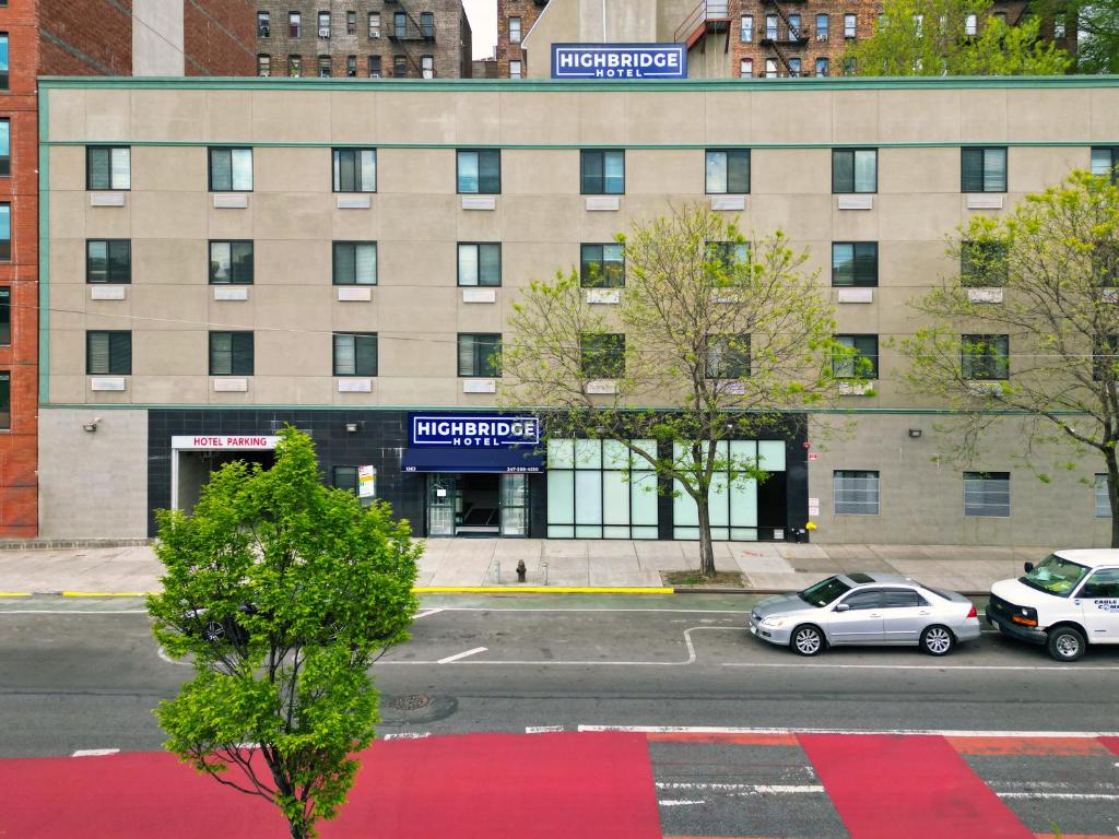 un edificio con coches estacionados frente a él en Highbridge Hotel, en Bronx