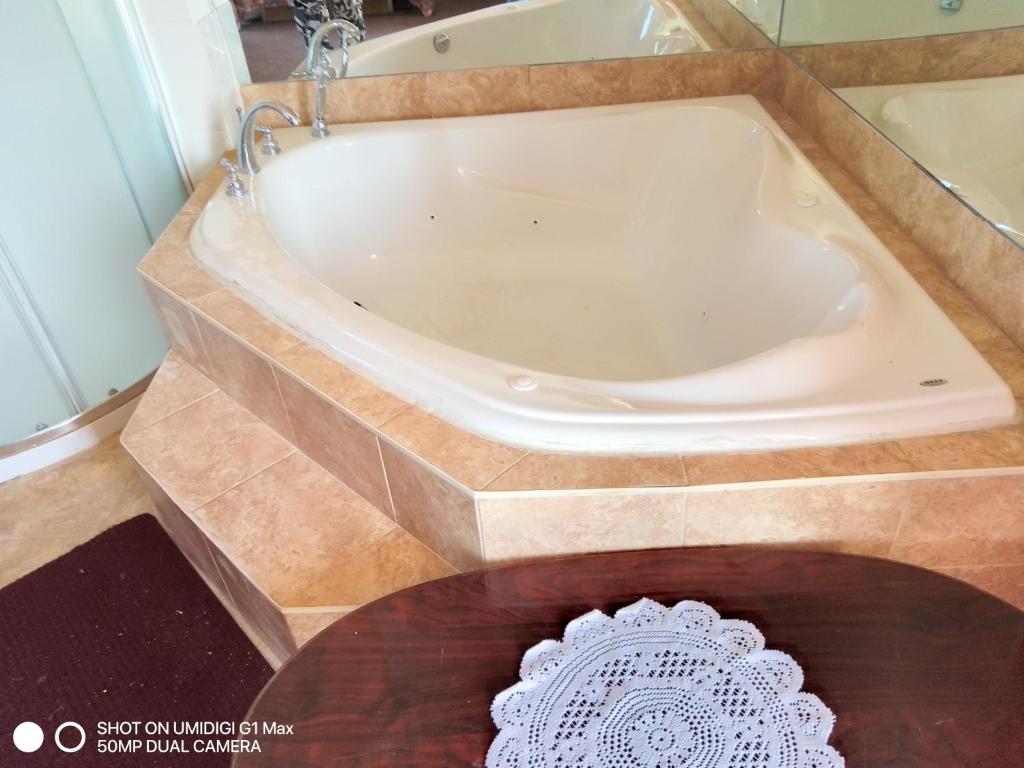 La salle de bains est pourvue d'une baignoire et d'une table en bois. dans l'établissement Motel Sainte Catherine, à Sainte-Catherine