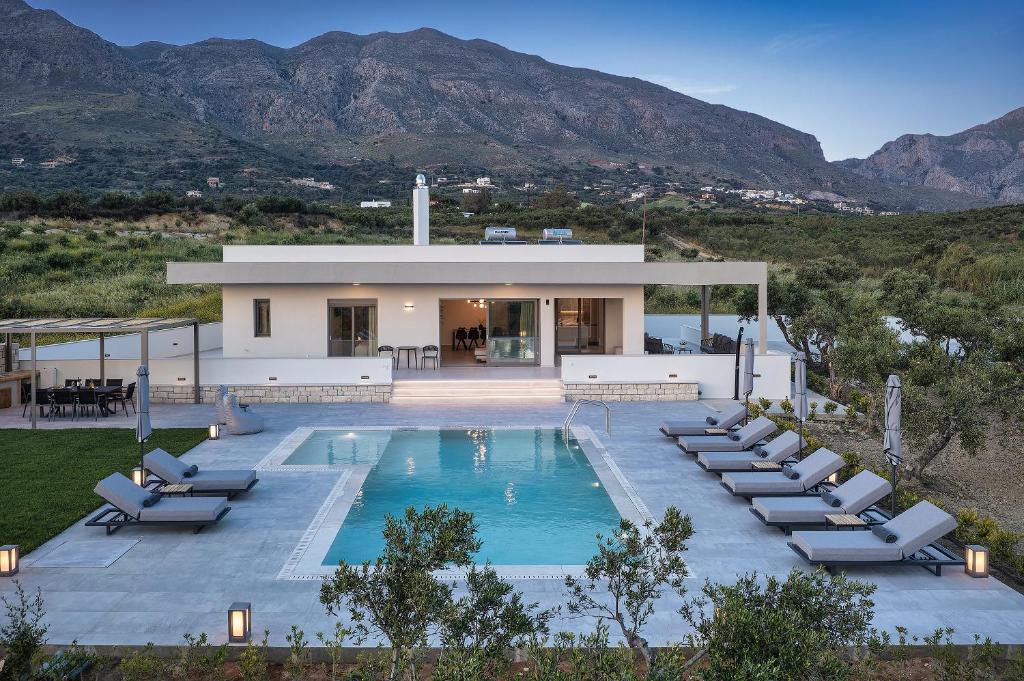 a house with a swimming pool and lounge chairs at Demar Exclusive Villa in Plakias