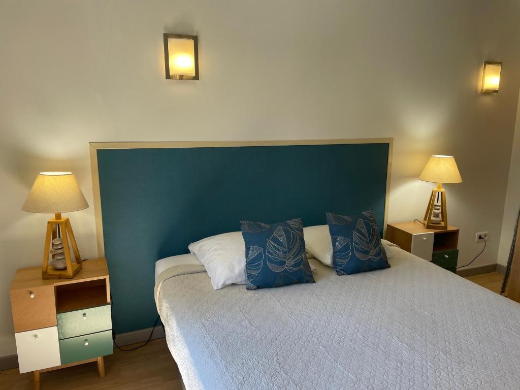 une chambre avec un lit avec une tête de lit bleue et deux lampes dans l'établissement Jolie petite maison Avignon - Montfavet, à Montfavet