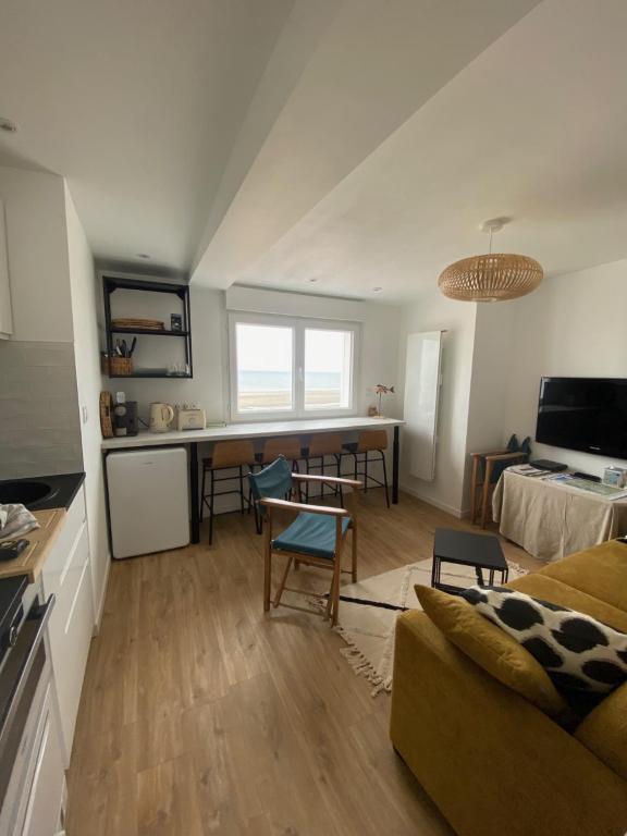 a living room with a couch and a table and a kitchen at L’Abri Cotier - Appartement face mer 2/4 personnes in Fort-Mahon-Plage