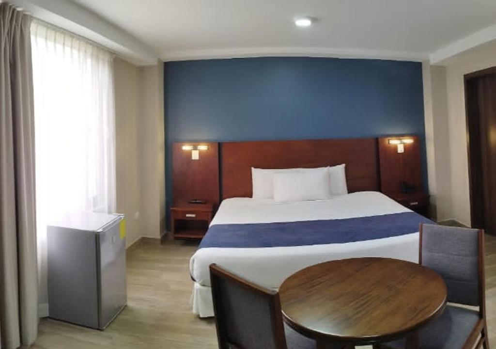 1 dormitorio con cama grande y mesa de madera en Hotel San Agustin Plaza, en Latacunga