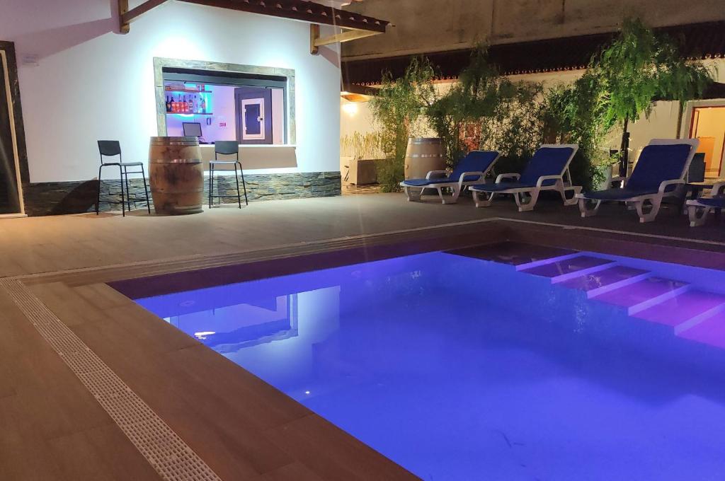 uma piscina com luzes azuis num quarto com cadeiras em Luxury Palm Suites em Reguengos de Monsaraz