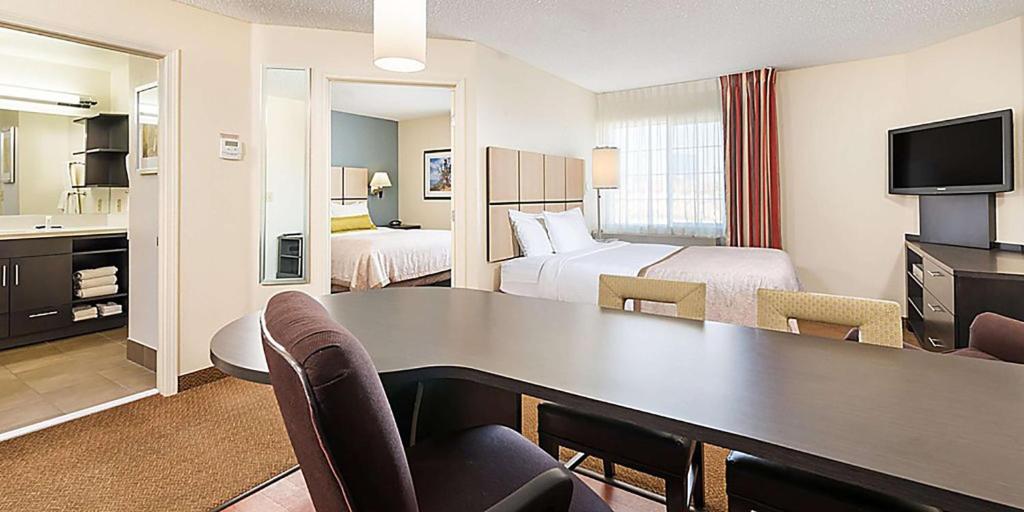 Sonesta Simply Suites Pittsburgh Airport في Imperial: غرفة في الفندق بها مكتب وغرفة بها سريرين