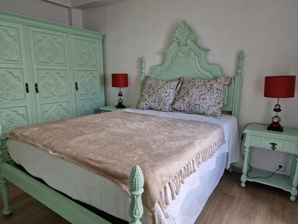 a bedroom with a green bed with two tables and two lamps at Apartamentos Garrett in Horta