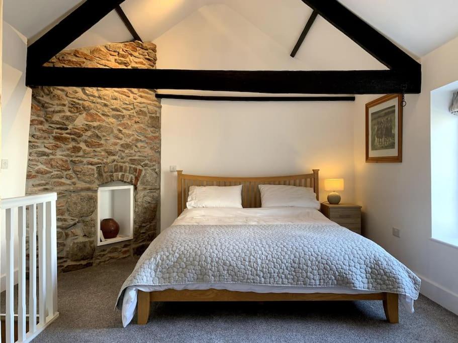 a bedroom with a bed and a stone wall at The Vottage - 3 bed cottage in Plymouth