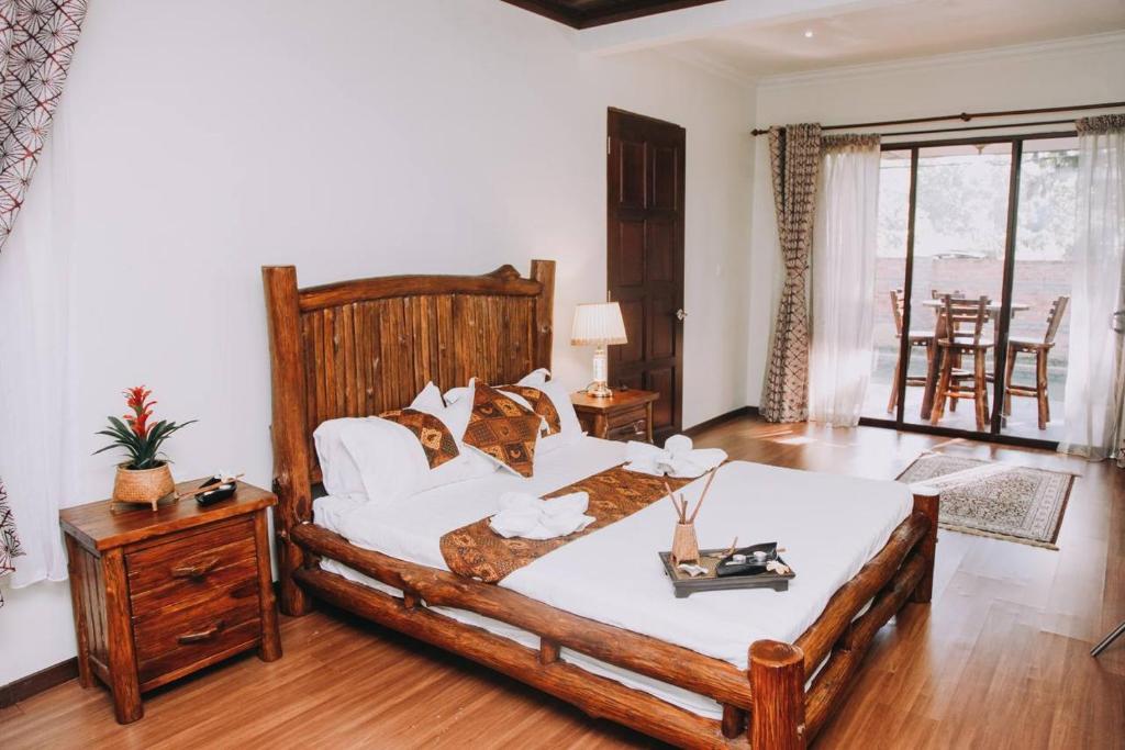 Un dormitorio con una gran cama de madera con sábanas blancas. en 101 Resort & Spa, Janda Baik, en Kampong Sum Sum