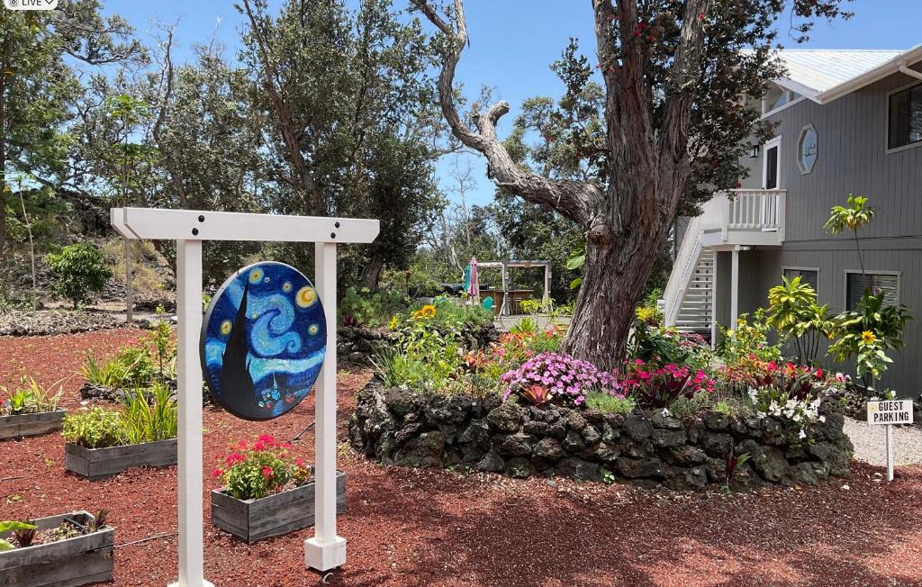 a sign in front of a garden with flowers at The Art Garden- Hibiscus Guesthouse in Hawaiian Ocean View