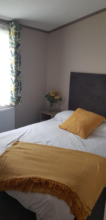 a bedroom with a bed with a yellow blanket on it at Warner Lane in Selsey