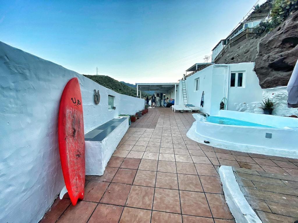 une planche de surf rouge penchée contre un mur à côté d'un bâtiment dans l'établissement Villa Cueva Tecen Valsequillo, à Valsequillo de Gran Canaria