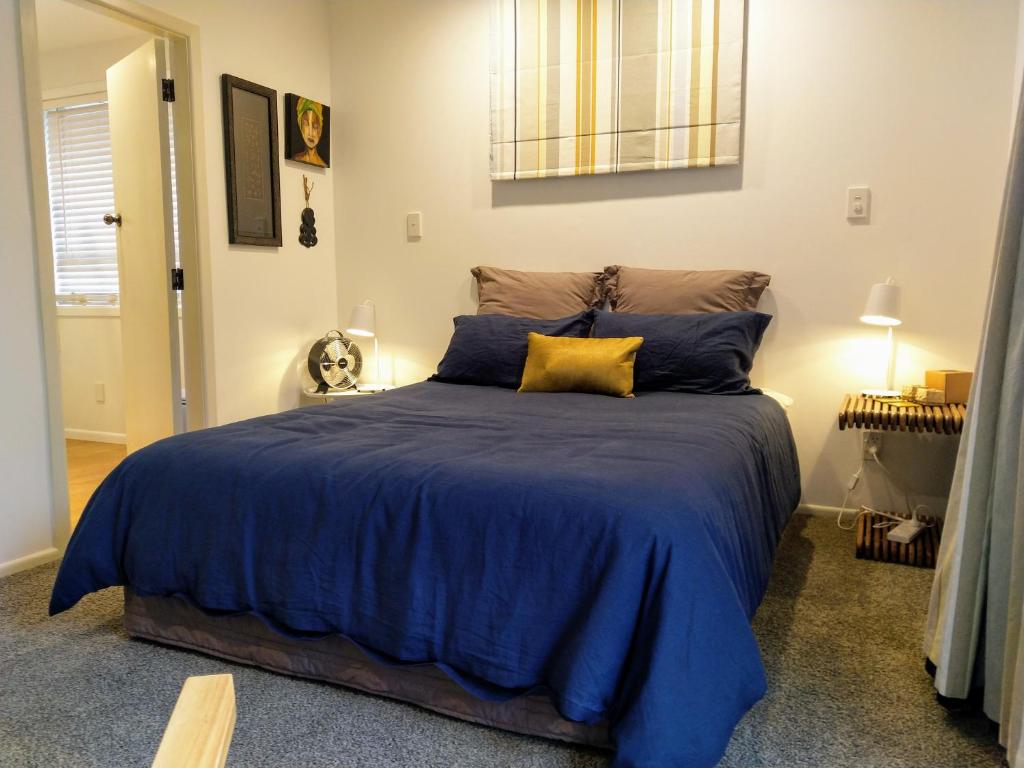 a bedroom with a large bed with a blue comforter at A little bit of country on the city's doorstep in Napier