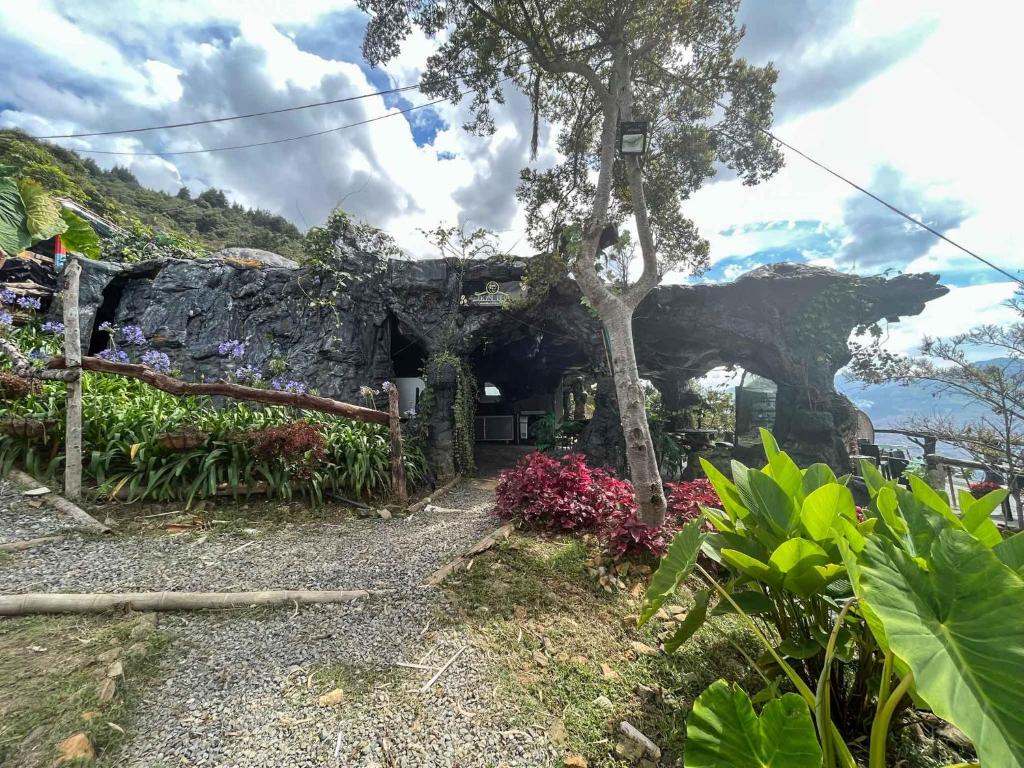 a stone house with a tree and flowers at Cabaña Parque Arvi vista panorámica in Medellín