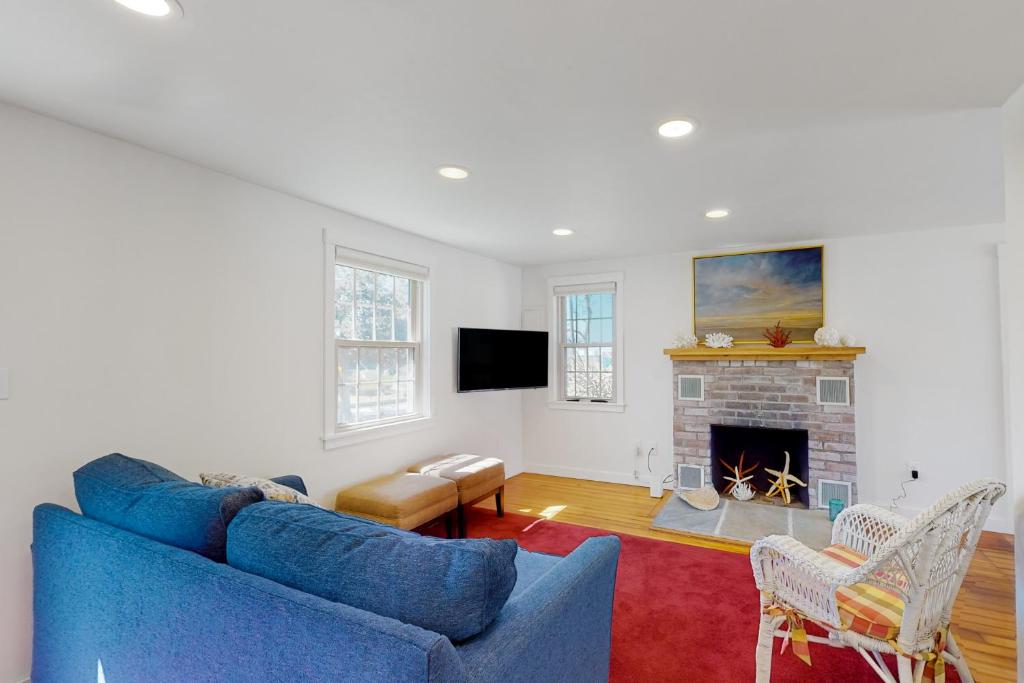 a living room with a blue couch and a fireplace at Adventures on Buzzards Bay in Bourne