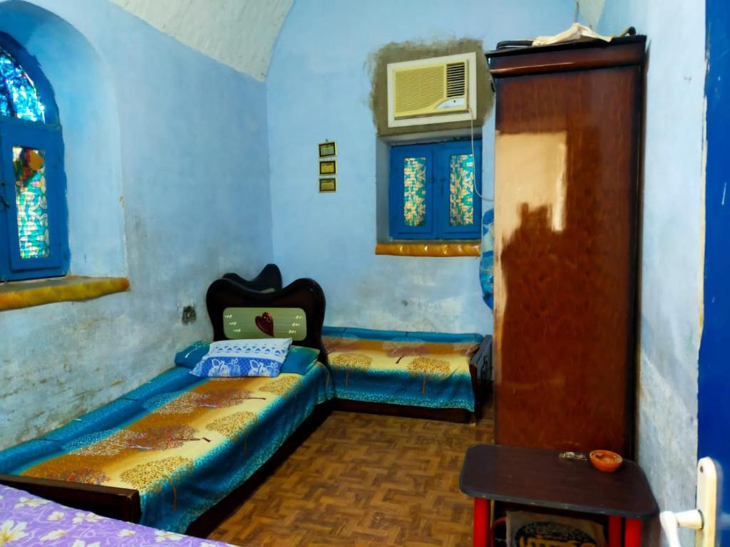 um quarto com duas camas e uma porta e janelas em البيت النوبي em Naj‘ al Maḩaţţah