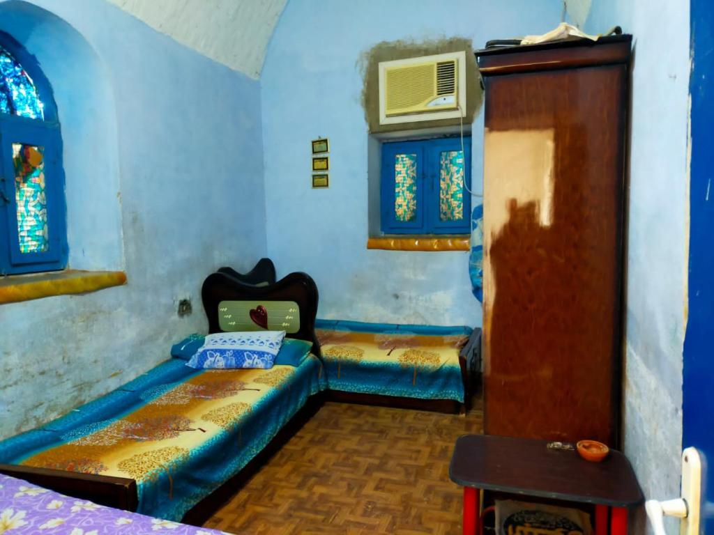 a room with two beds and a door and windows at البيت النوبي in Naj‘ al Maḩaţţah